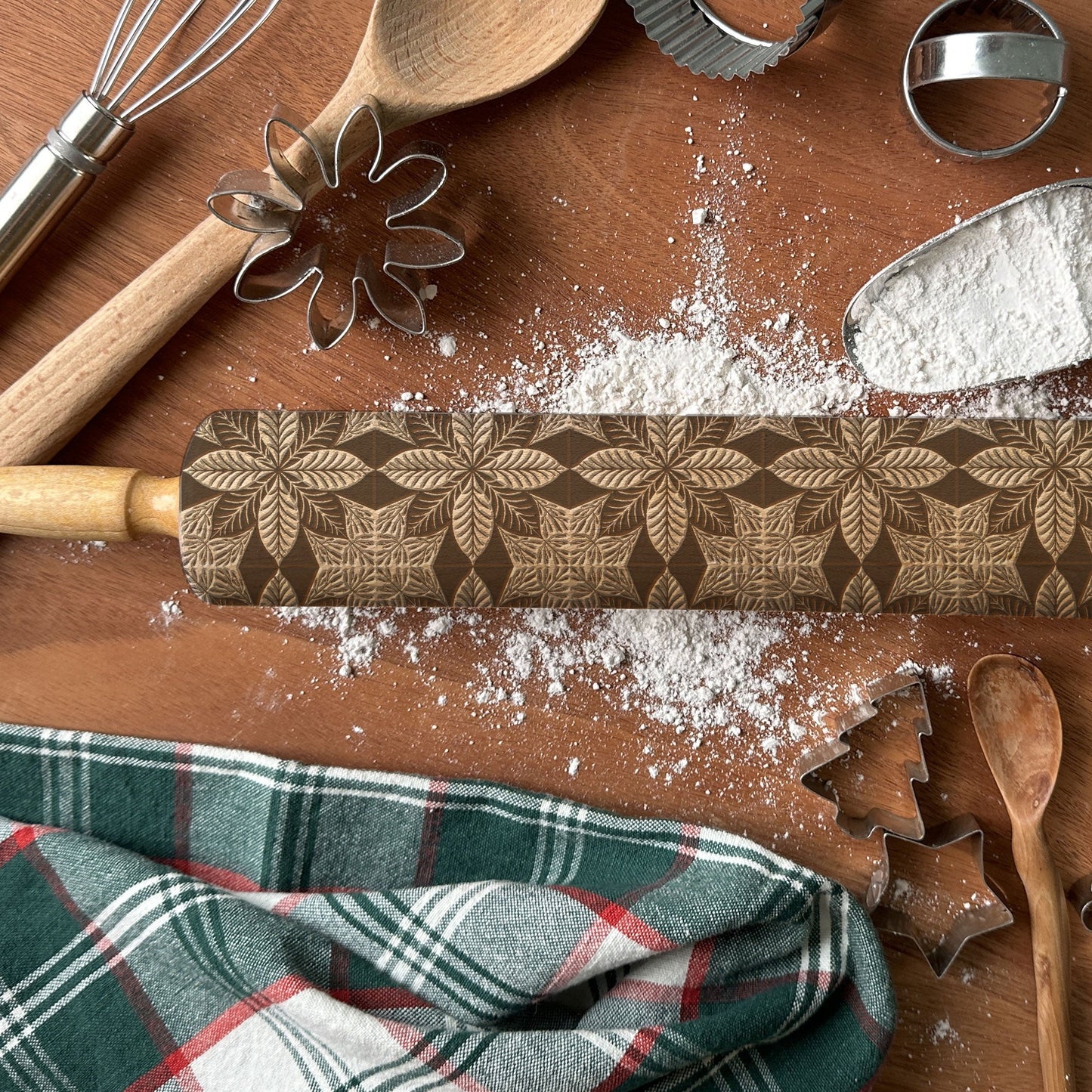 Baking tools including a rolling pin, wooden spoon, and cookie cutters on a wooden surface with flour.