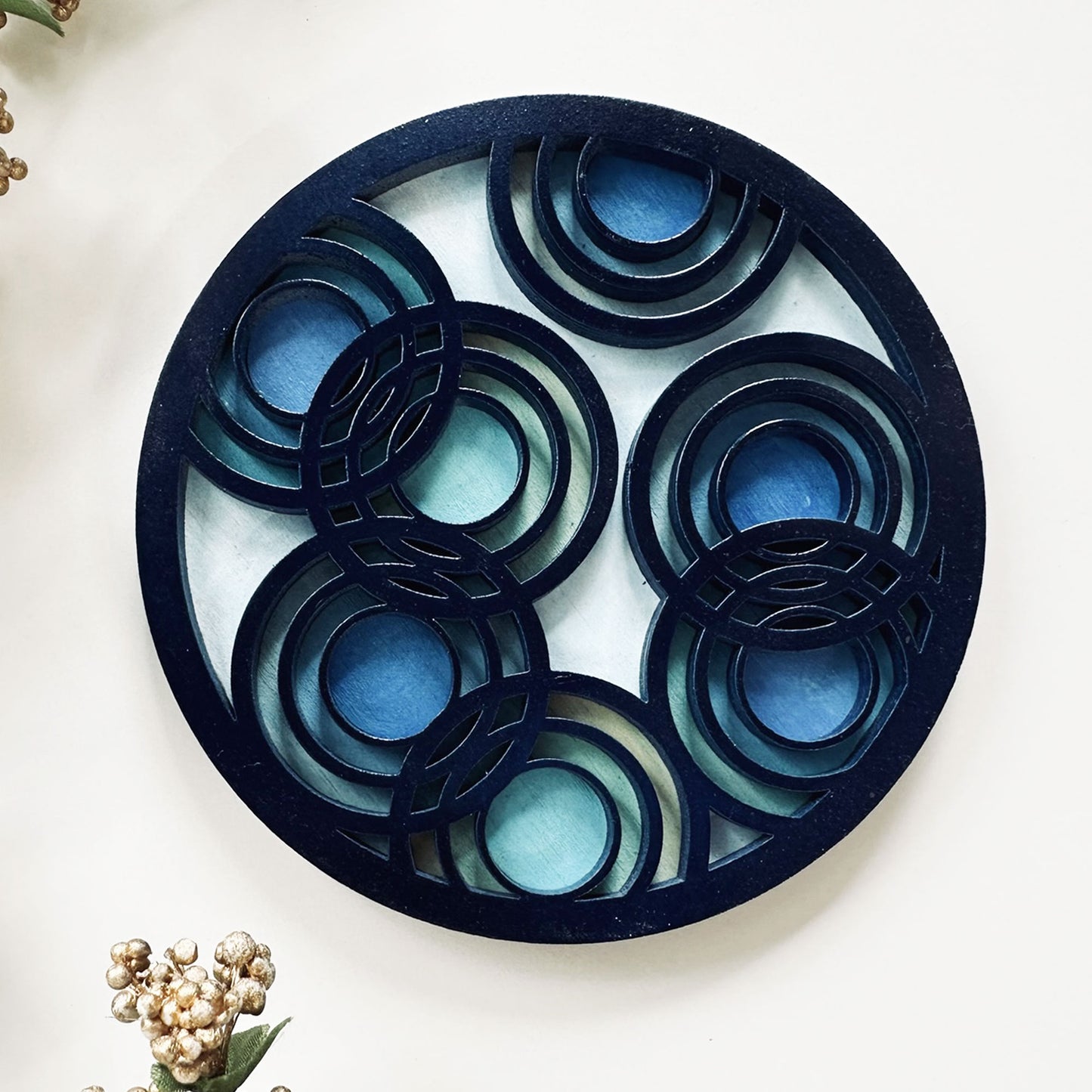 Decorative circular coaster with concentric blue and black rings on a light background