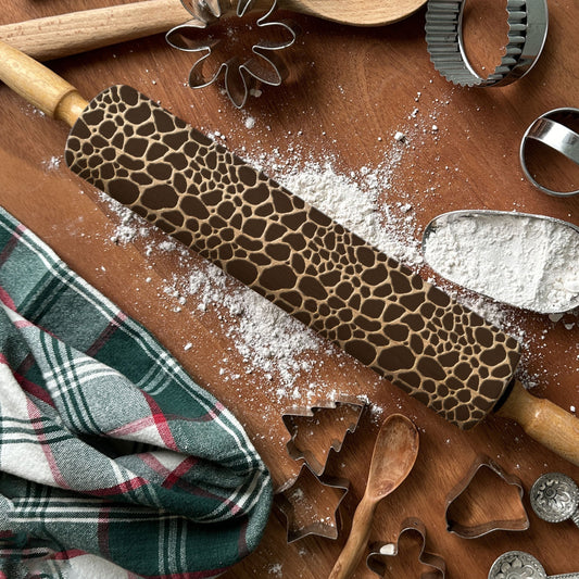 Wooden rolling pin with a pattern on a wooden surface with baking tools and flour.