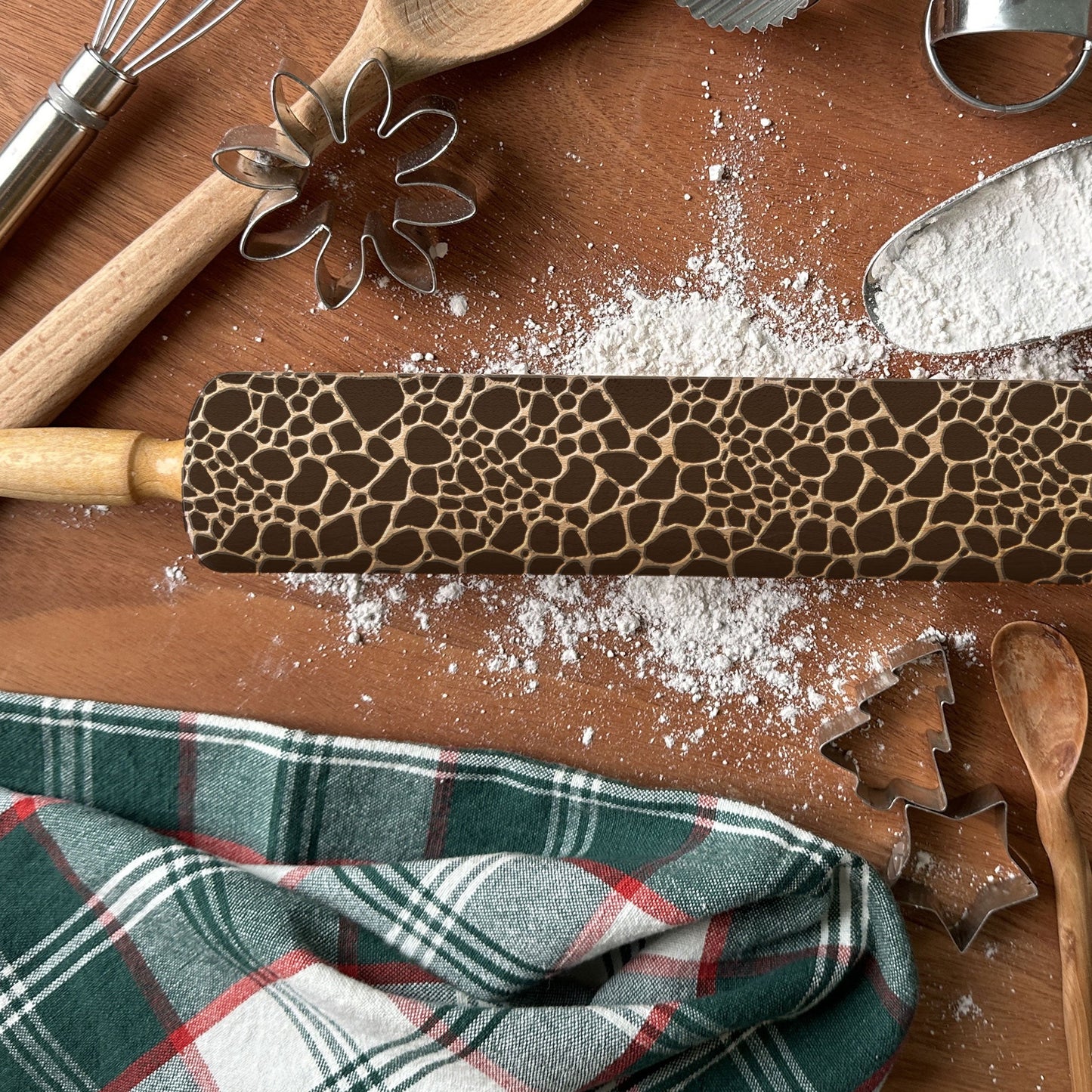 Decorative rolling pin with a pattern on a wooden surface with flour and baking tools.