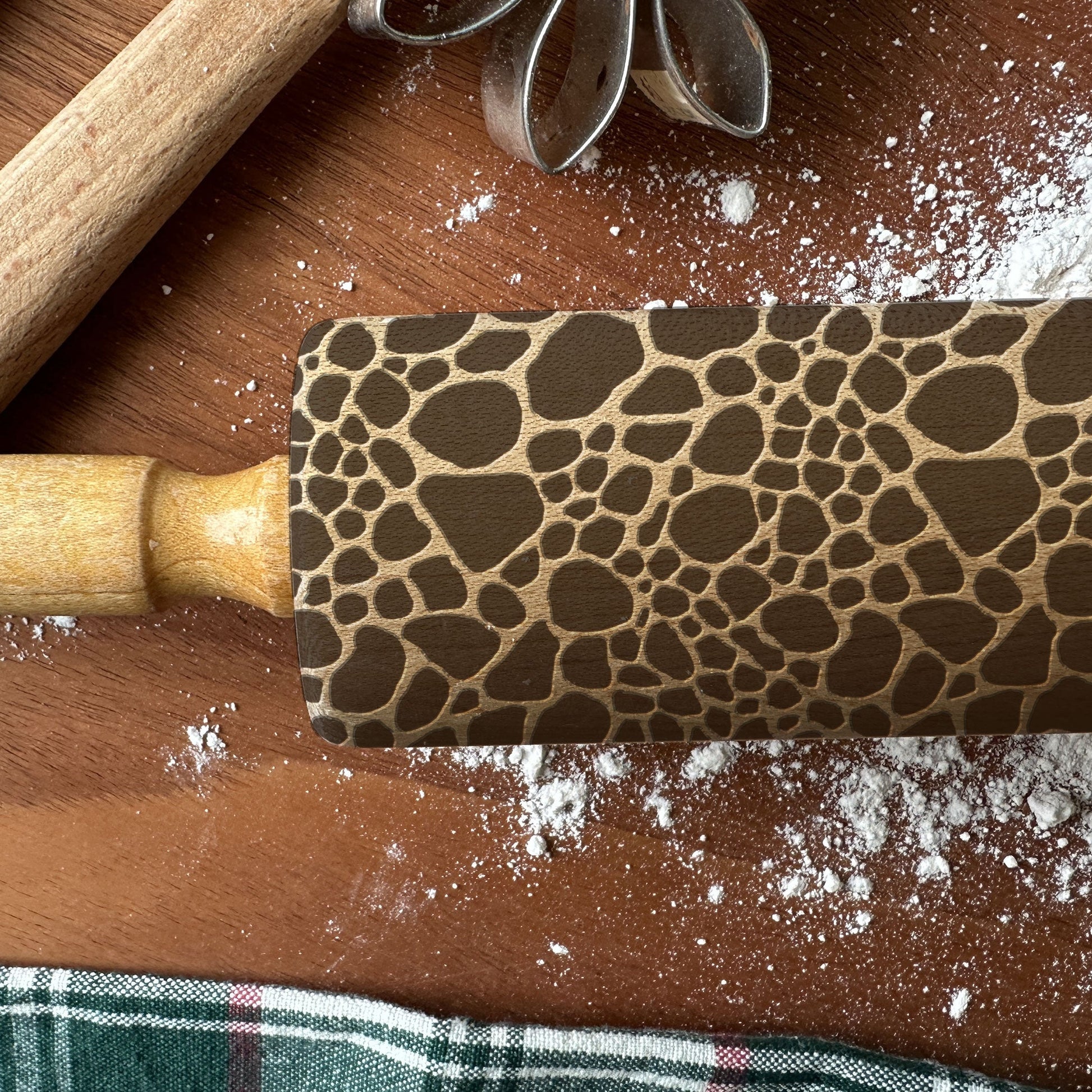Rolling pin with a textured pattern on a wooden surface with flour.
