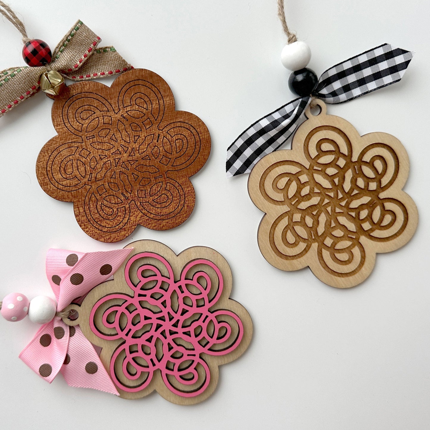 Decorative wooden ornaments with floral patterns and colorful ribbons on a white background
