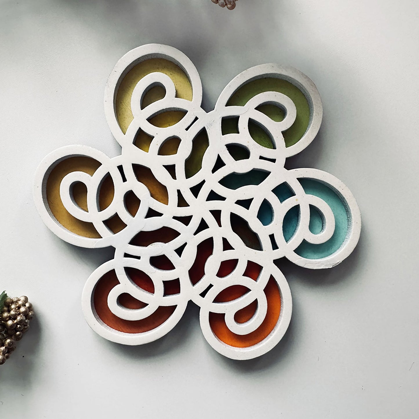 Decorative coaster with interlocking circular designs in various colors on a light gray background.