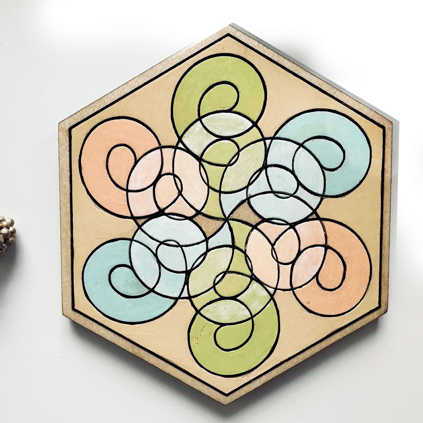 Hexagonal wooden coaster with colorful circular design on a white background