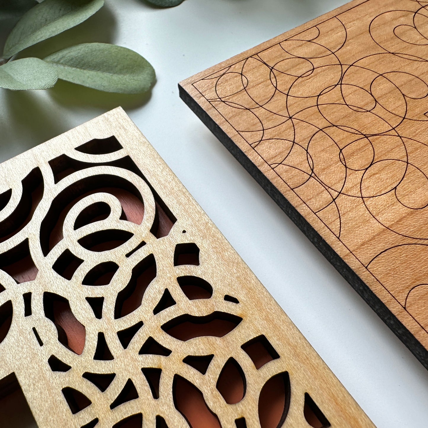 Two wooden panels with intricate cut-out patterns on a white surface.
