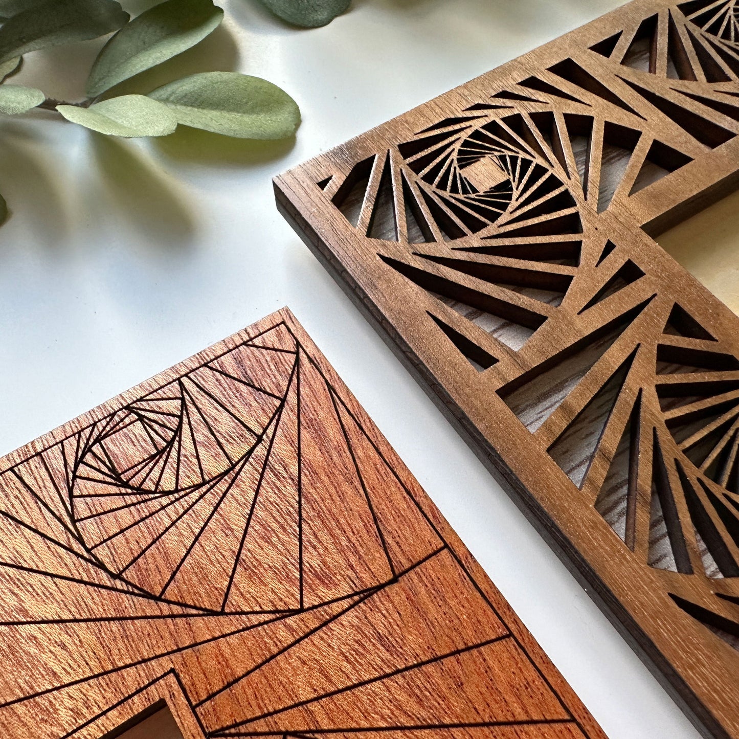 Two wooden coasters with geometric laser-cut designs on a light surface.