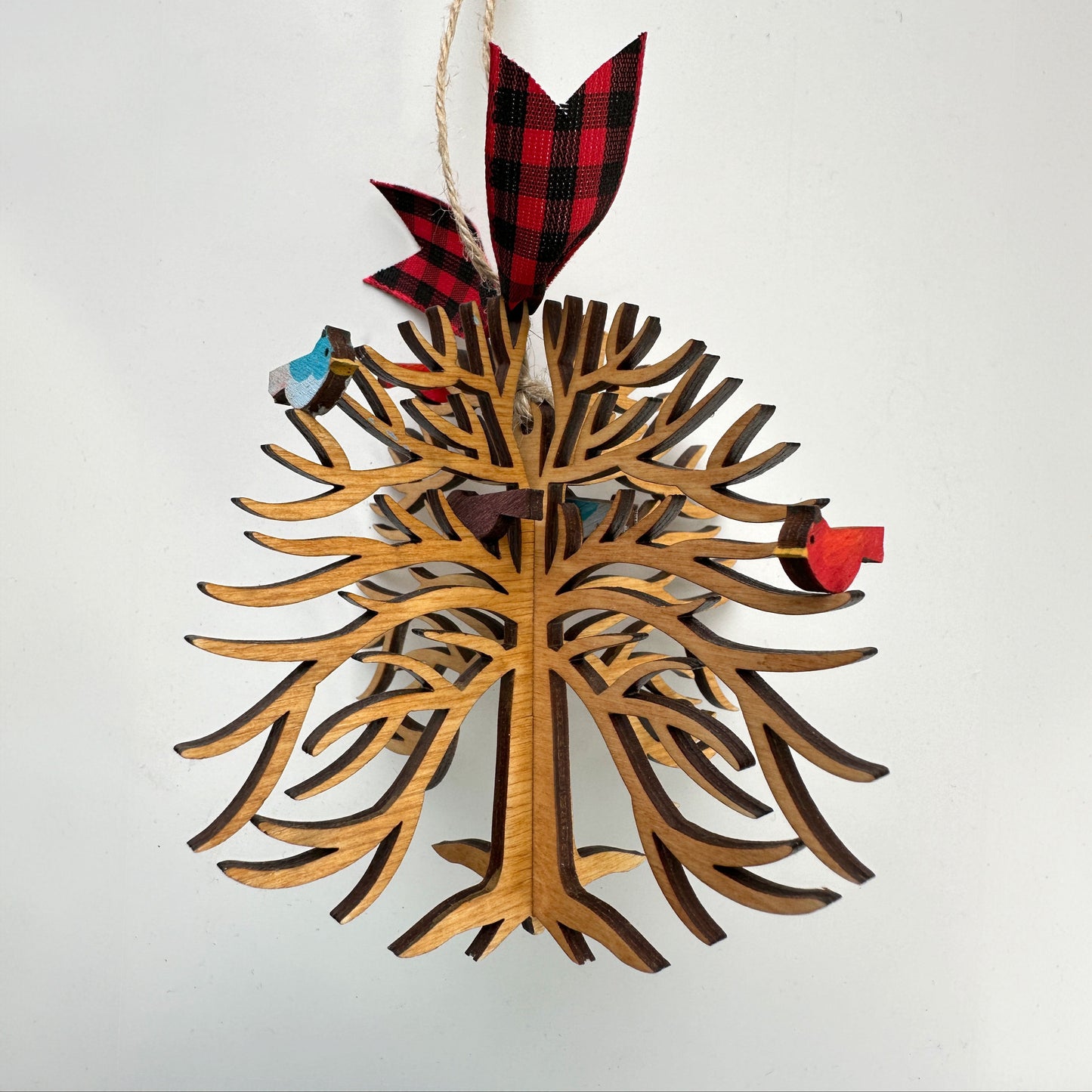 Wooden Christmas tree ornament with red and black plaid ribbon on a white background