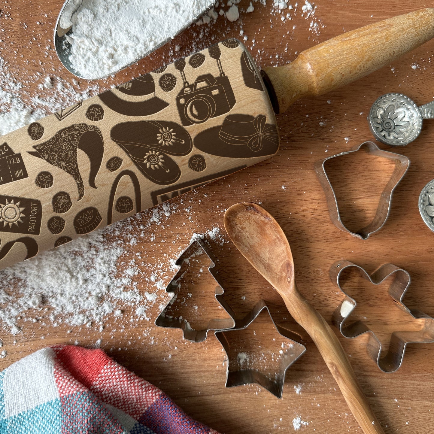 Wooden cookie cutters and rolling pin on a wooden surface with flour.