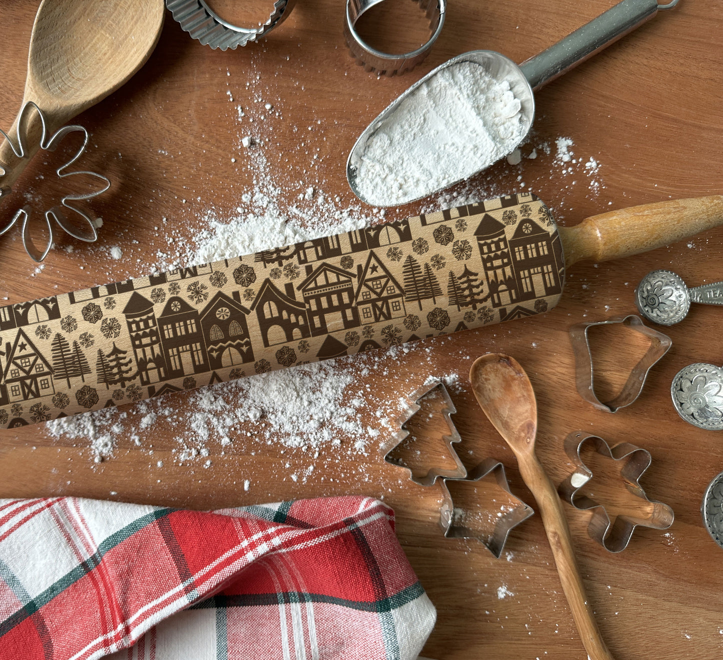 Wooden rolling pin with embossed patterns on a wooden surface with flour and cookie cutters.